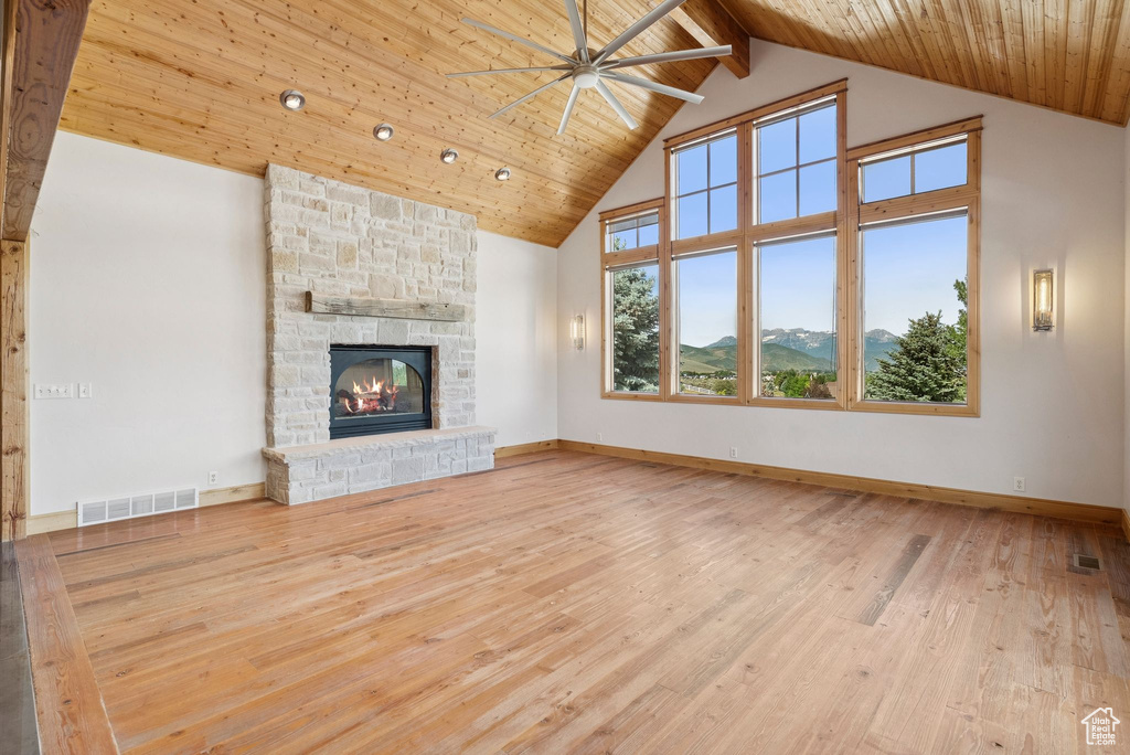 Unfurnished living room with high vaulted ceiling, a ceiling fan, a wooden ceiling with exposed beams, a fireplace, and wood finished floors