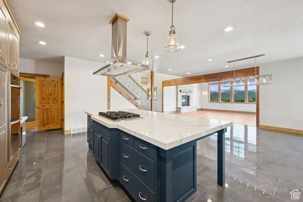 Kitchen with island range hood, stainless steel gas stovetop, a center island, open floor plan, and recessed lighting