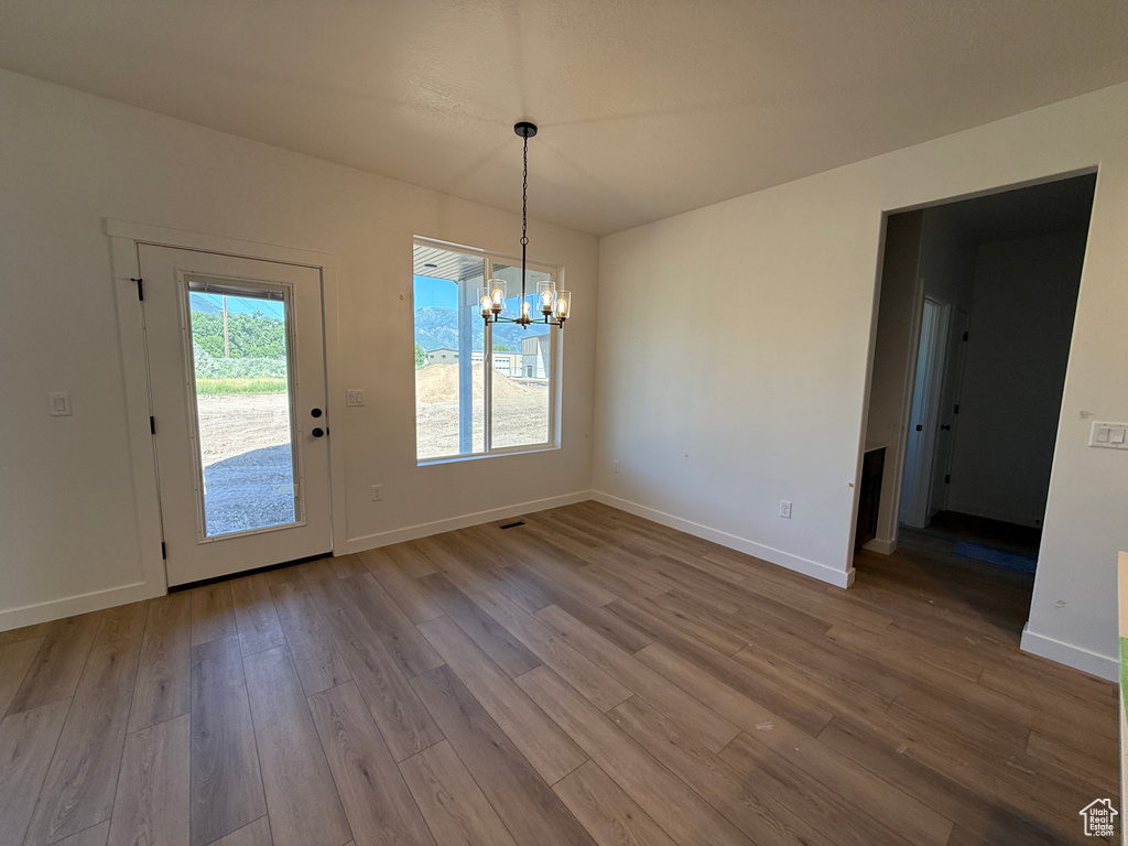 Unfurnished dining area with a chandelier and wood finished floors