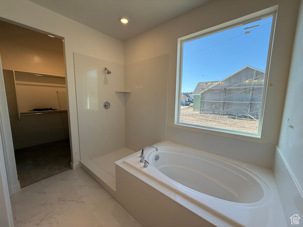 Bathroom featuring a garden tub, marble look tiles, a stall shower, a spacious closet, and recessed lighting