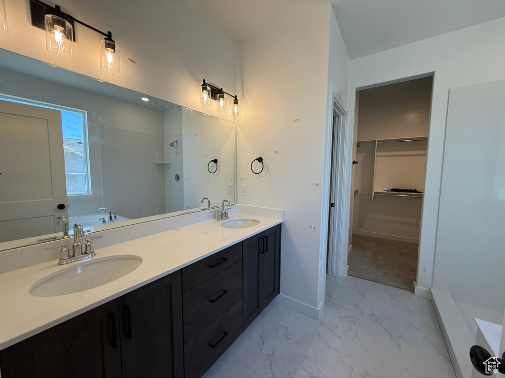 Bathroom with marble look tile flooring, double vanity, a walk in closet, and a bathtub