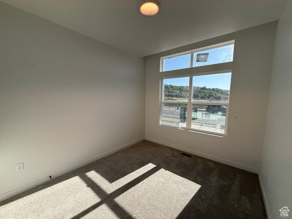 Unfurnished room with dark colored carpet and baseboards