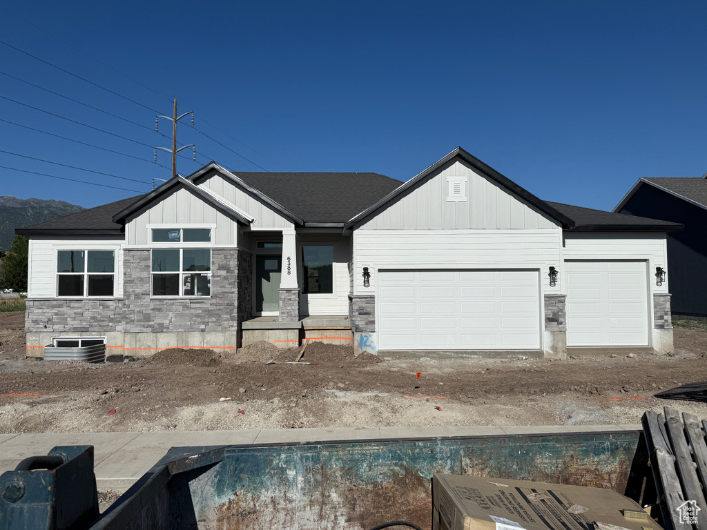 View of front of house featuring stone siding, board and batten siding, an attached garage, and driveway