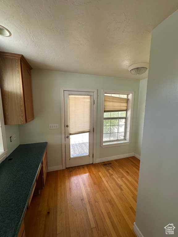 Doorway to outside with light wood-style flooring and a textured ceiling