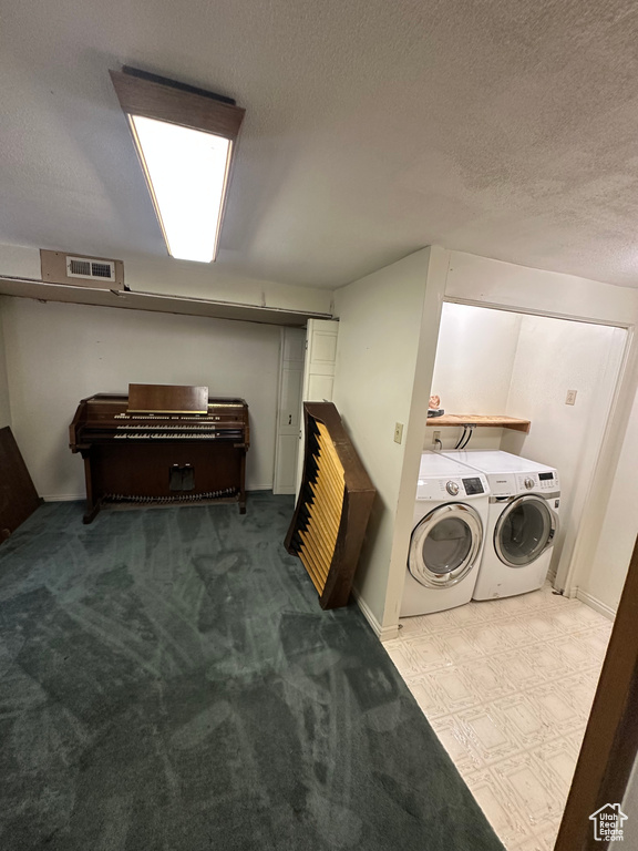 Laundry area featuring separate washer and dryer, a textured ceiling, and carpet flooring