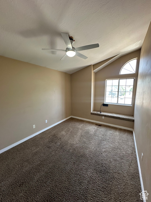 Unfurnished room with vaulted ceiling, ceiling fan, carpet, and a textured ceiling