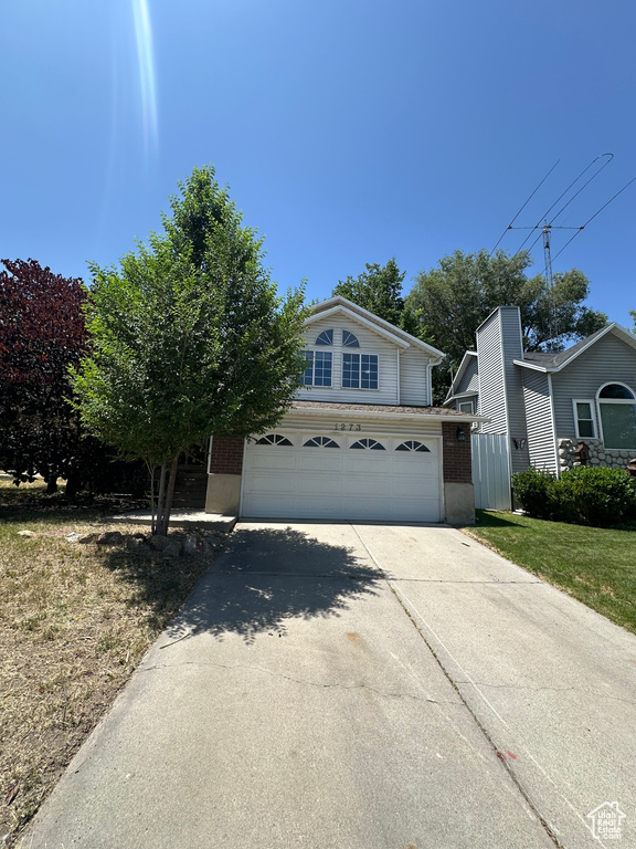 View of front facade featuring an attached garage, driveway, and brick siding