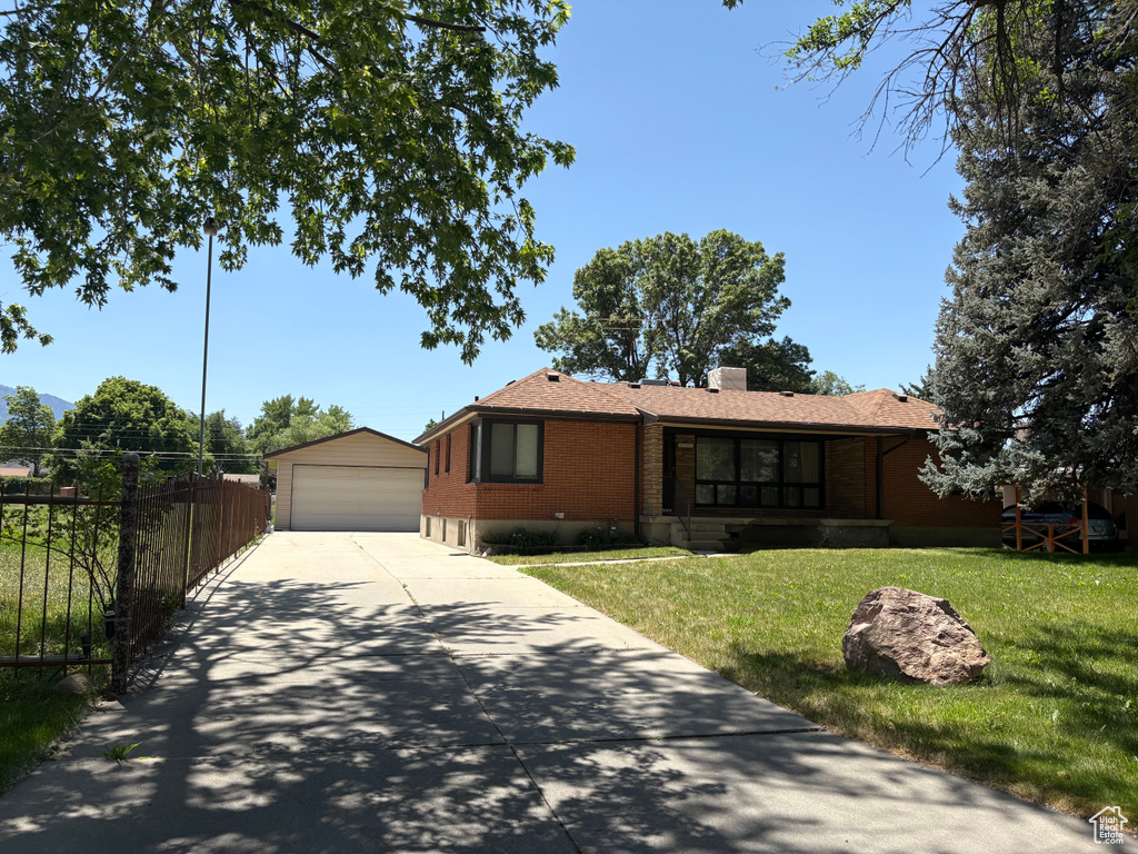 Ranch-style house featuring brick siding, a garage, an outdoor structure, and a chimney