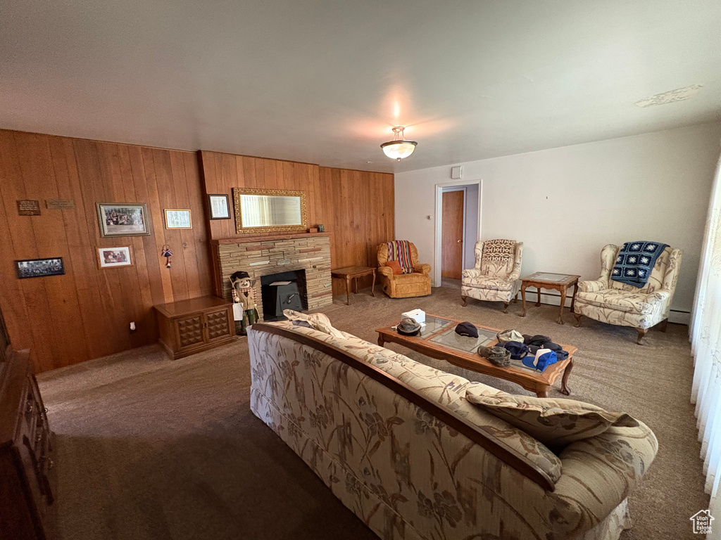 Living area featuring carpet, a stone fireplace, wooden walls, and a baseboard radiator