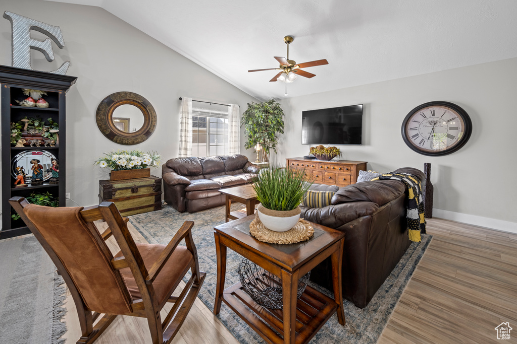 Living room with lofted ceiling, ceiling fan, and light wood-style flooring