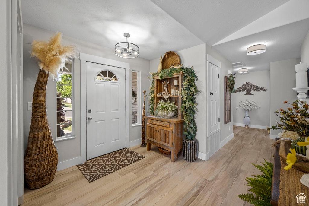 Entryway featuring light wood finished floors and a chandelier