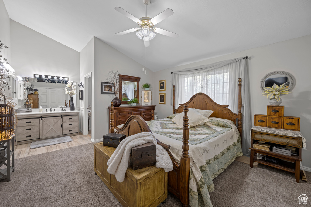 Bedroom with vaulted ceiling, light colored carpet, ceiling fan, and connected bathroom