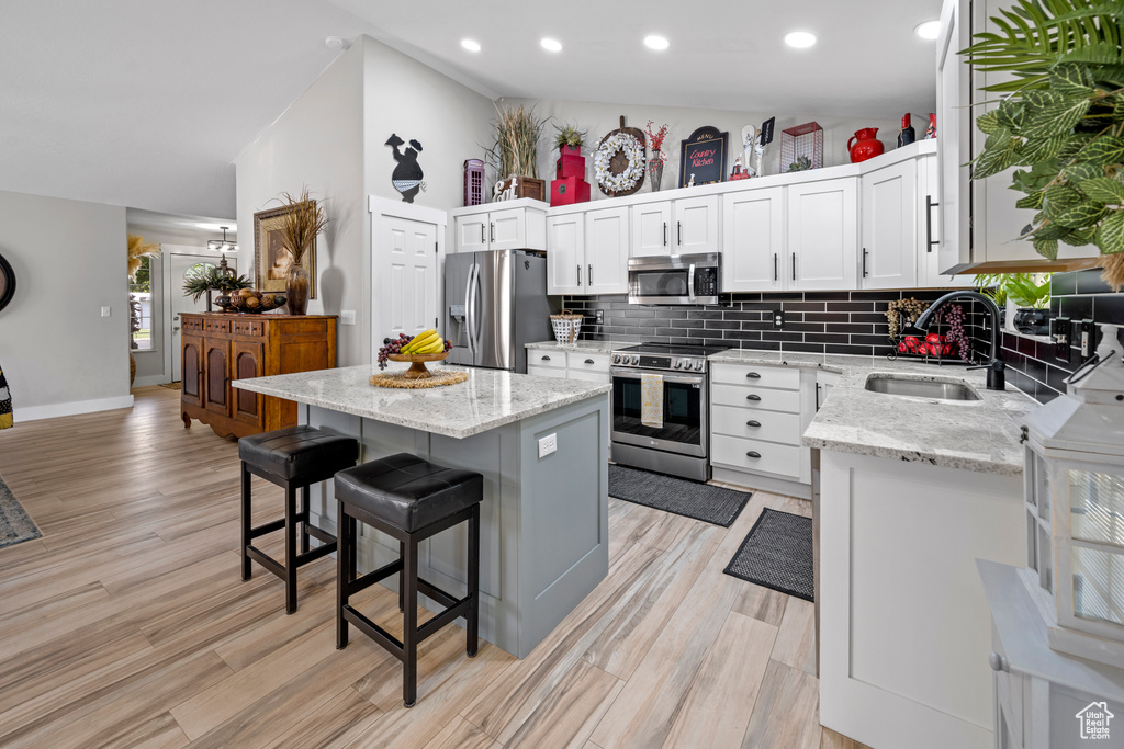 Kitchen featuring stainless steel appliances, light wood finished floors, tasteful backsplash, a kitchen breakfast bar, and recessed lighting