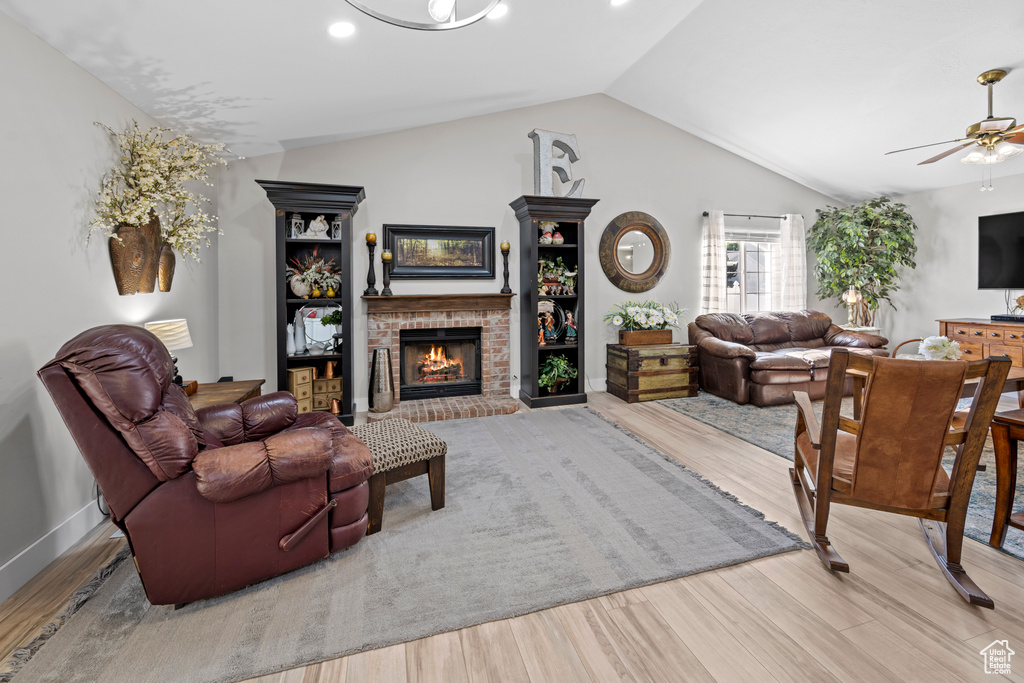 Living area with lofted ceiling, wood finished floors, a fireplace, ceiling fan, and recessed lighting