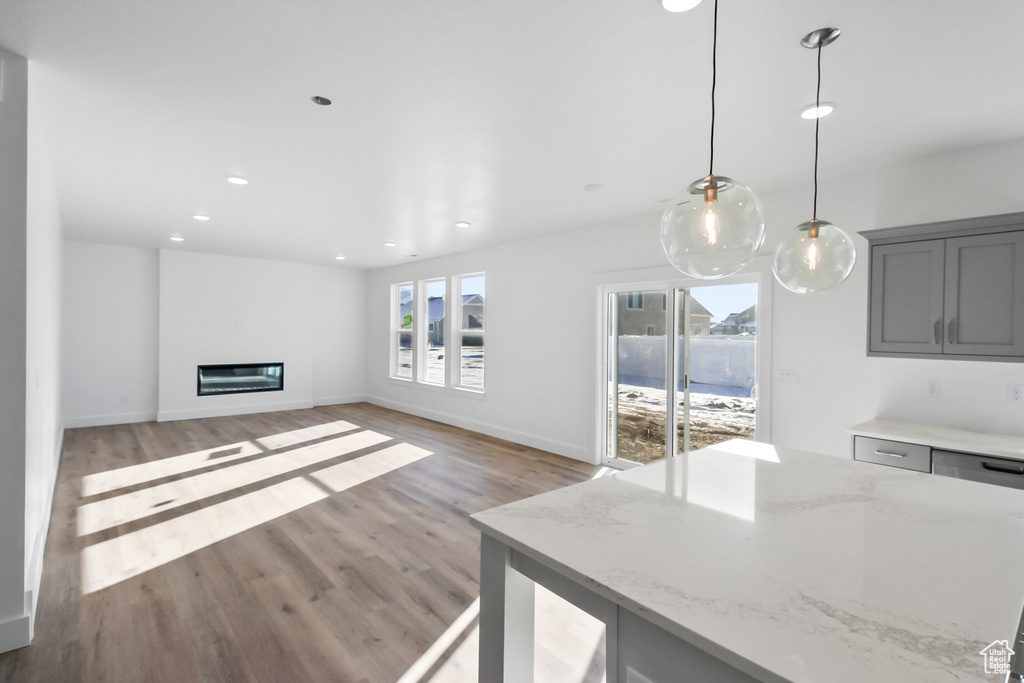 Unfurnished living room featuring plenty of natural light, light wood-type flooring, recessed lighting, and a glass covered fireplace
