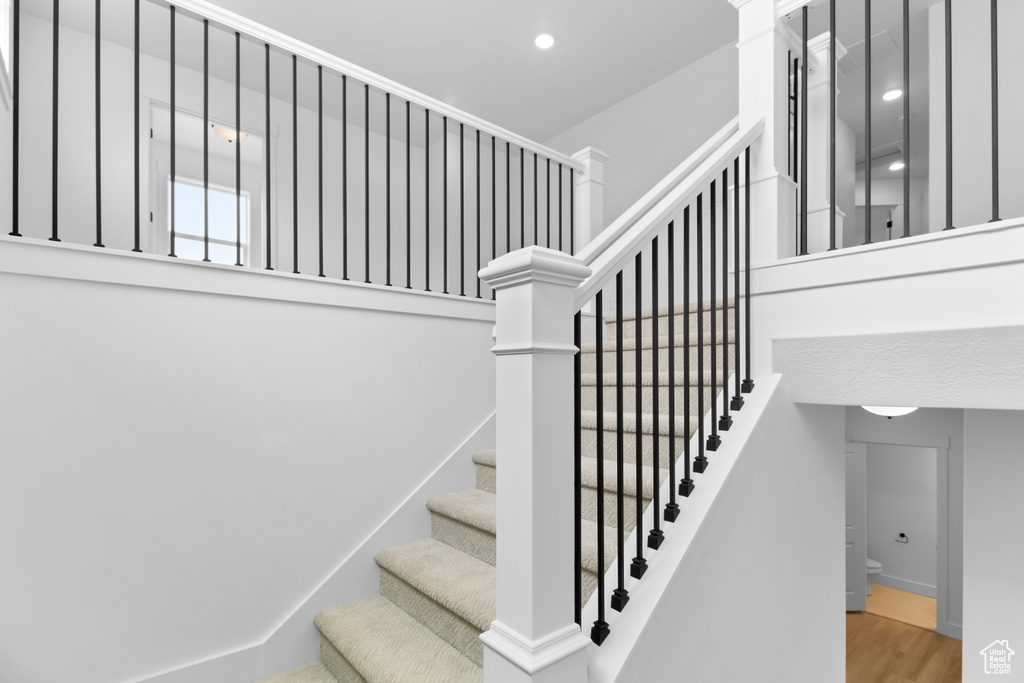 Staircase with wood finished floors and recessed lighting