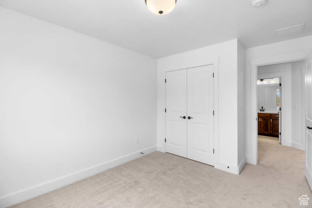 Unfurnished bedroom featuring light carpet and a closet