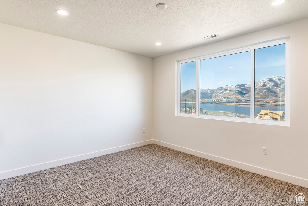 Spare room featuring light carpet, recessed lighting, a water and mountain view, and a textured ceiling