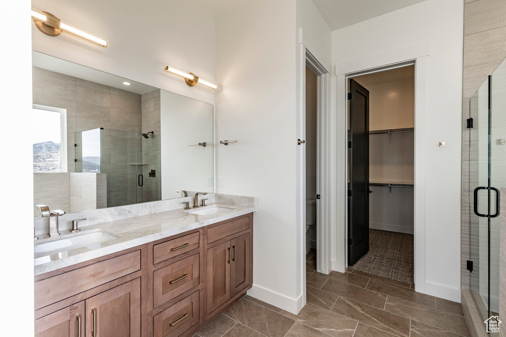 Bathroom with a shower stall, double vanity, and a spacious closet