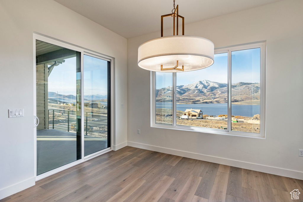 Empty room with wood finished floors, a mountain view, and healthy amount of natural light