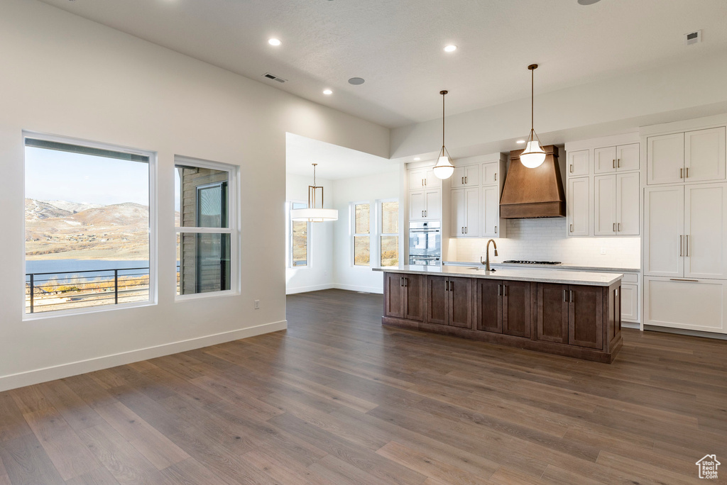 Kitchen with custom exhaust hood, white cabinetry, tasteful backsplash, light countertops, and recessed lighting