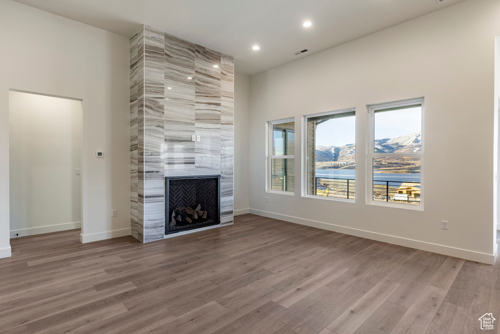 Unfurnished living room with a large fireplace, wood finished floors, and recessed lighting