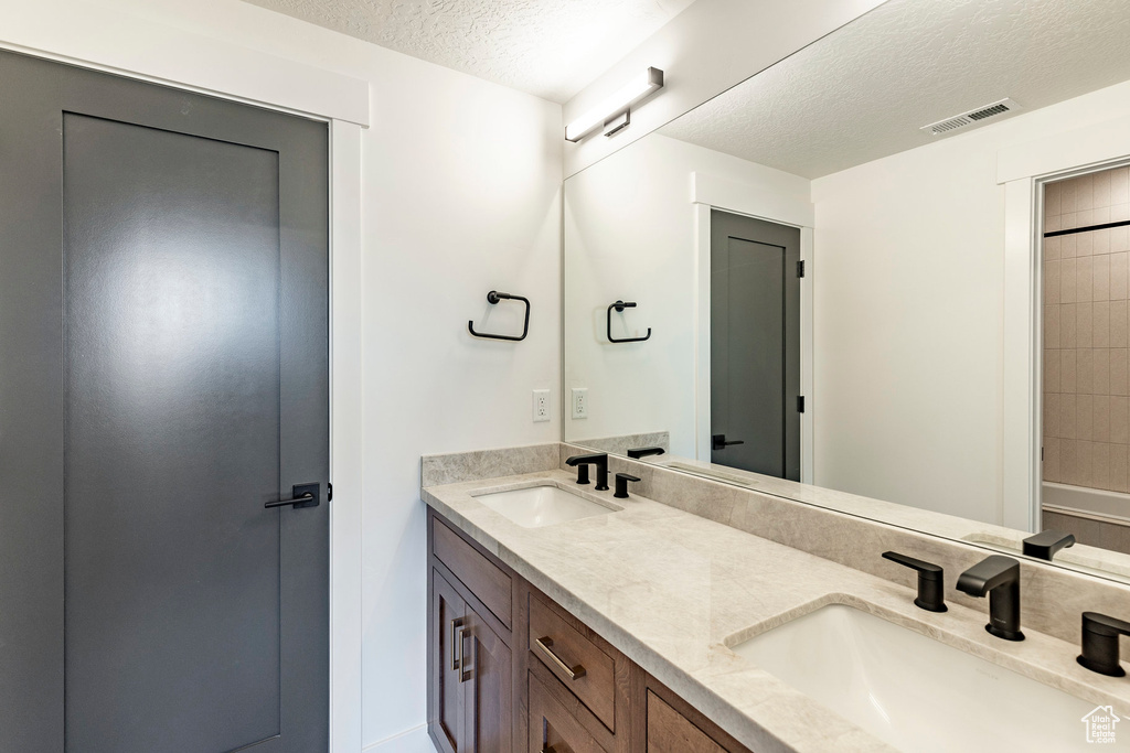 Bathroom with a textured ceiling and double vanity