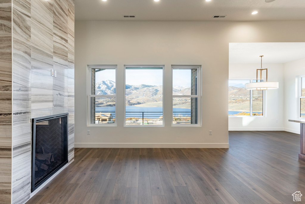 Unfurnished living room with a tiled fireplace, dark wood-type flooring, and recessed lighting