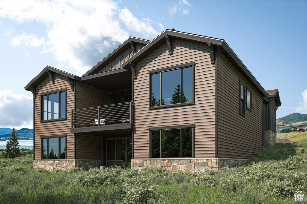 Back of house with a balcony, stone siding, a mountain view, and board and batten siding