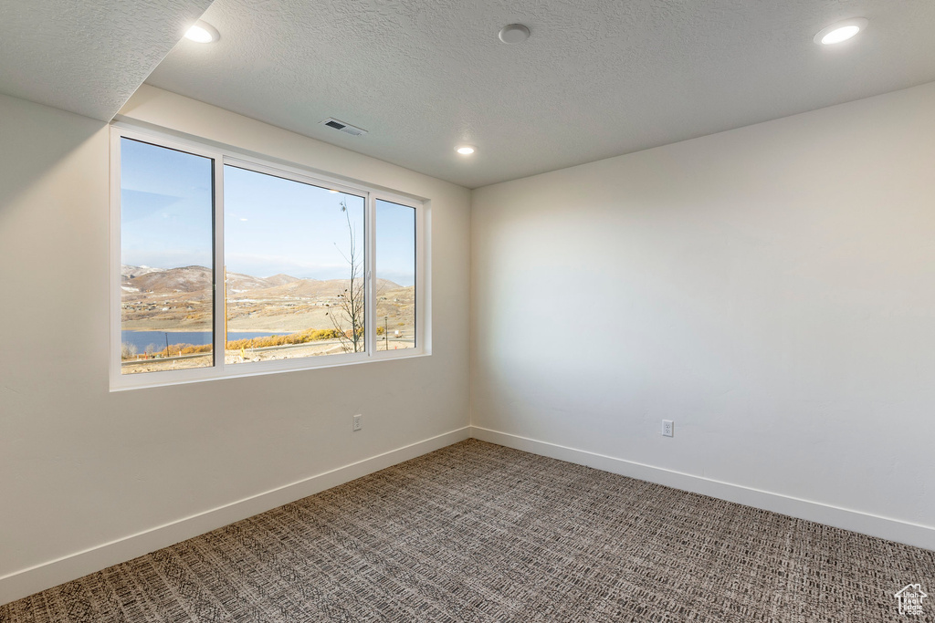 Carpeted empty room with recessed lighting and a mountain view