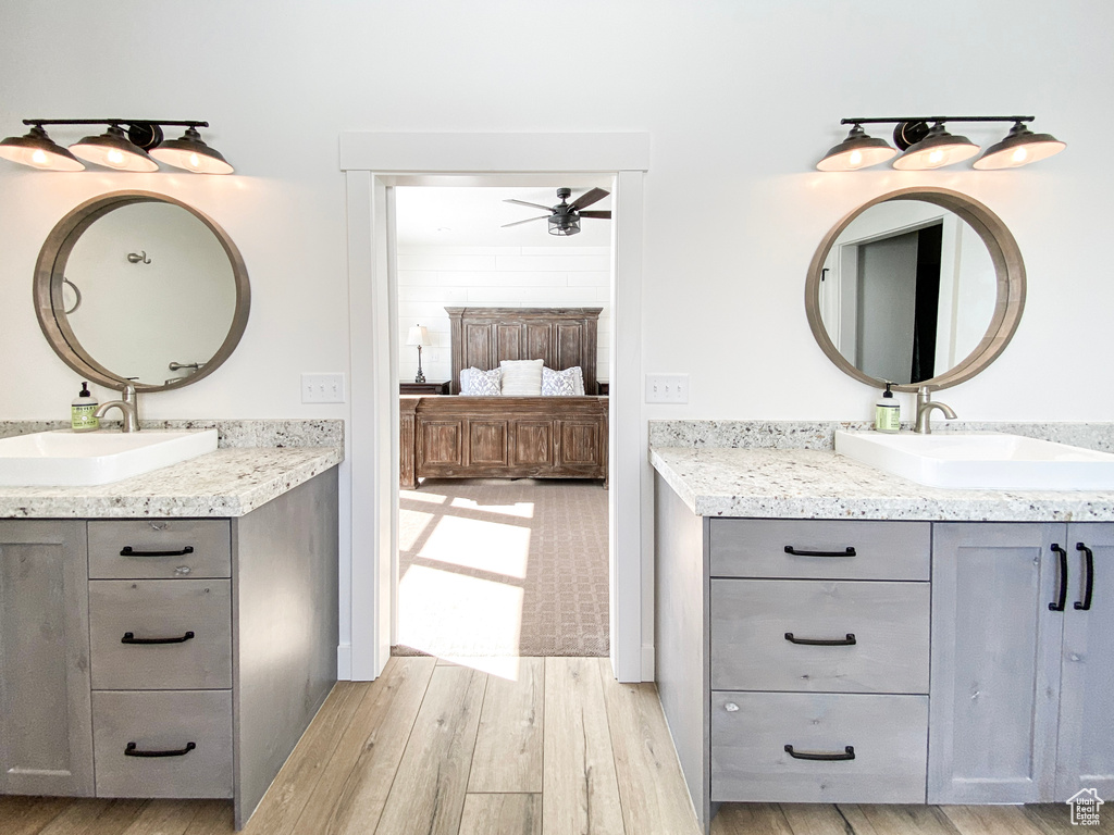 Ensuite bathroom with ceiling fan, wood finished floors, and two vanities