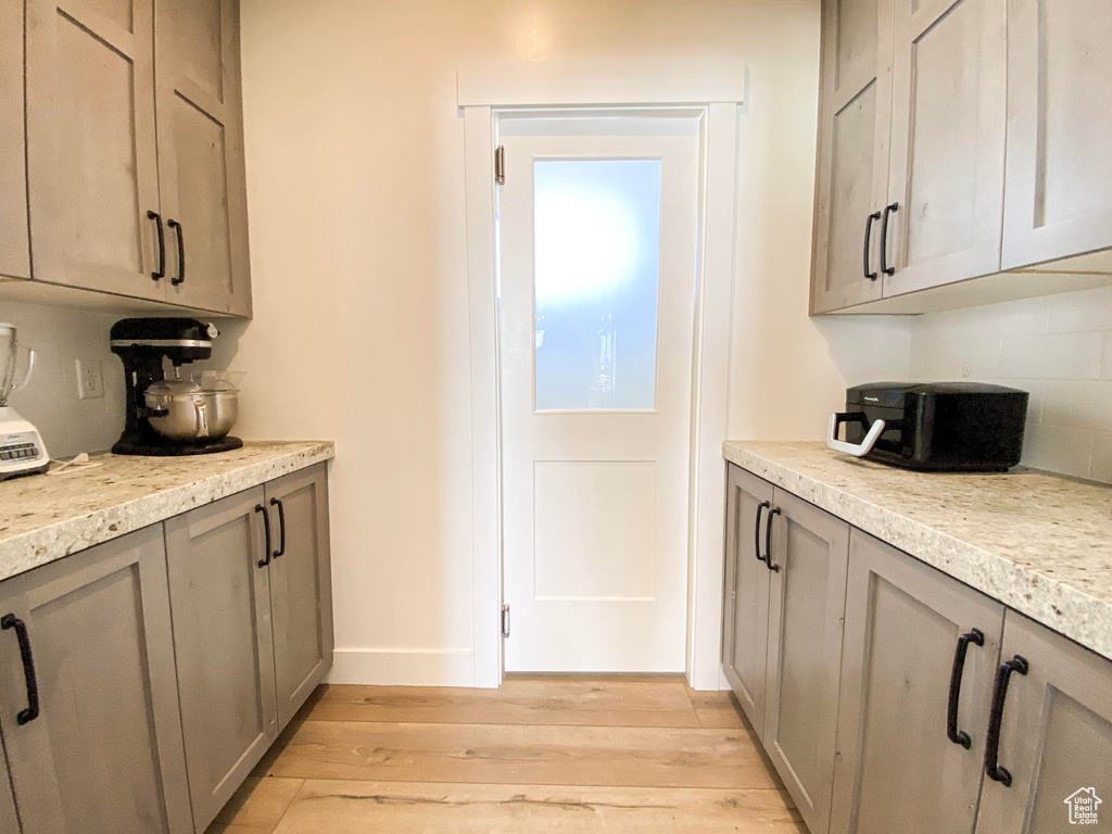 Kitchen with gray cabinetry, tasteful backsplash, light wood-style floors, and light countertops