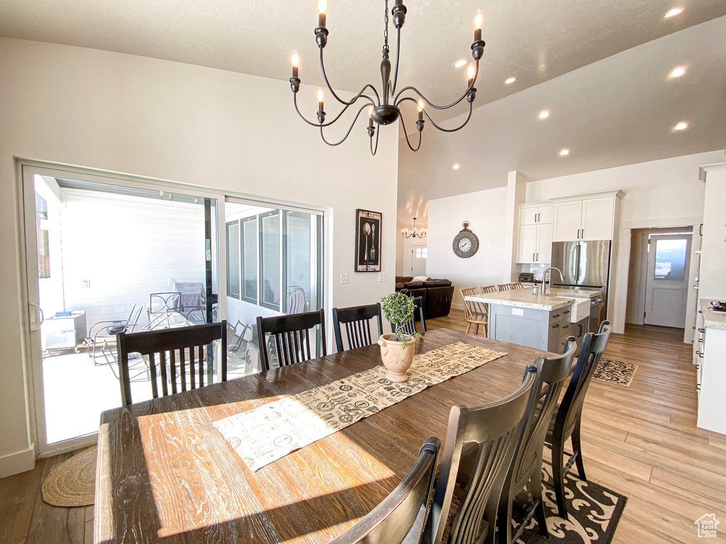 Dining room with a chandelier, recessed lighting, light wood-style flooring, and a towering ceiling