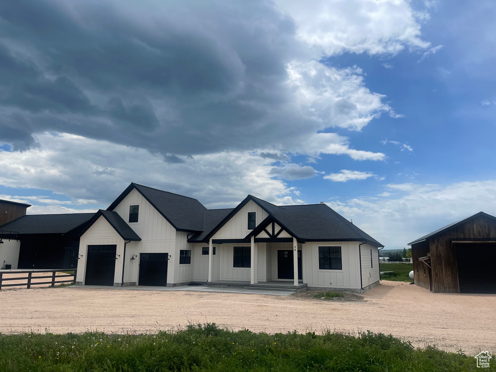 Modern farmhouse featuring driveway, a porch, and board and batten siding
