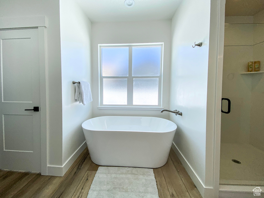 Full bathroom with wood finished floors, a freestanding tub, and a shower stall