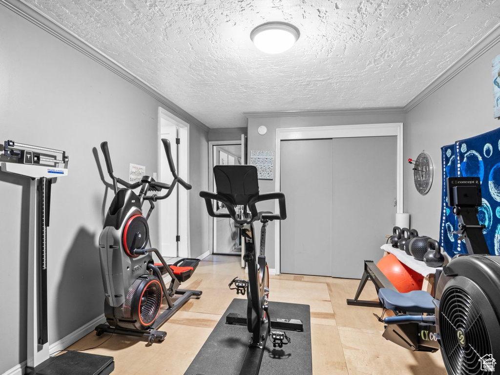 Workout room with crown molding and a textured ceiling