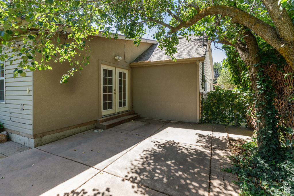 Rear view of house with french doors, roof with shingles, a patio, and stucco siding