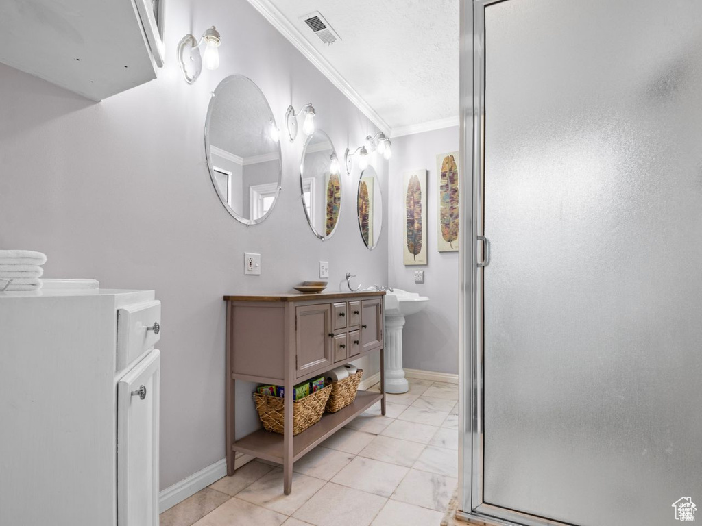 Full bath with crown molding, a stall shower, marble finish flooring, and double vanity