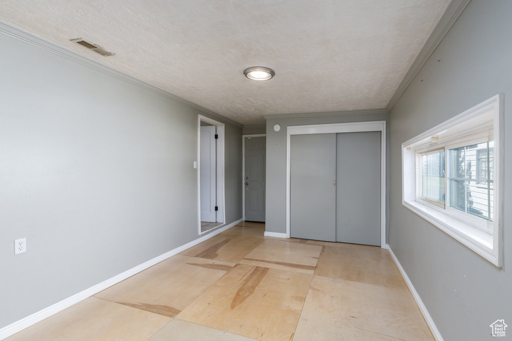 Unfurnished bedroom with a closet, a textured ceiling, and ornamental molding