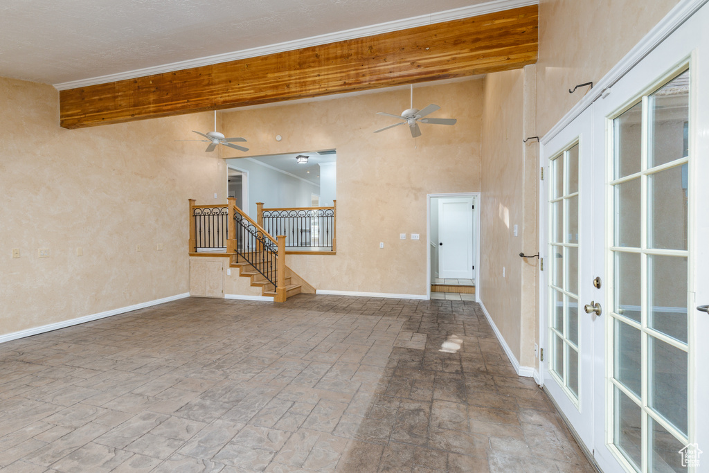 Spare room featuring a ceiling fan, french doors, stairway, crown molding, and a towering ceiling