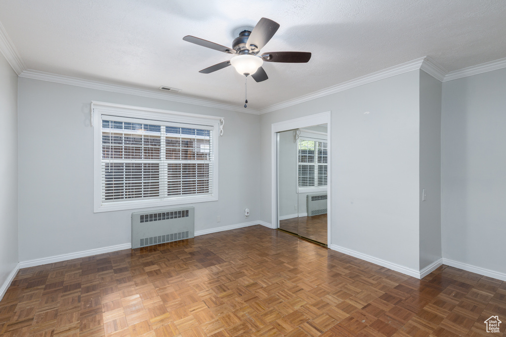 Unfurnished room featuring radiator heating unit, a ceiling fan, and crown molding