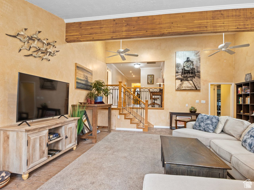 Living area with a ceiling fan, ornamental molding, stairway, and tile patterned flooring