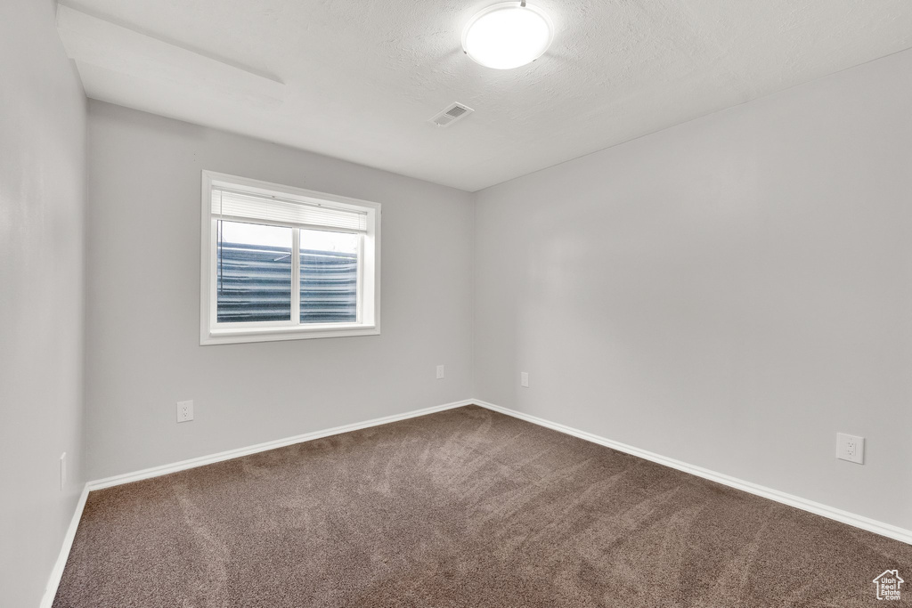 Empty room featuring dark carpet