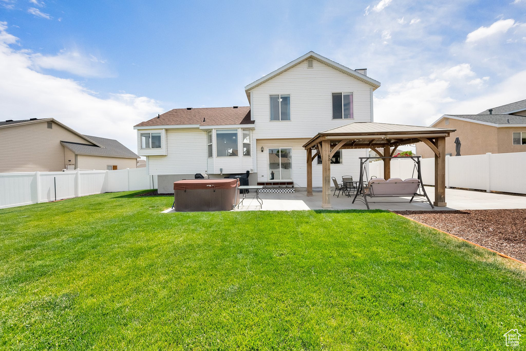Back of property featuring a hot tub, a gazebo, a patio, and a fenced backyard