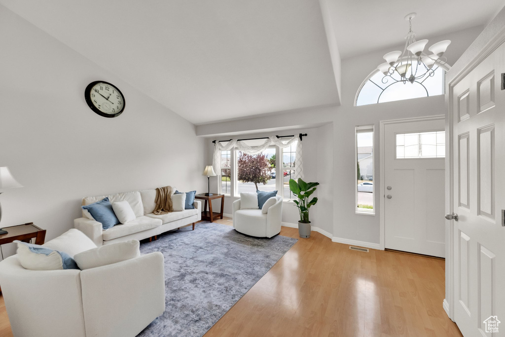 Living area featuring a chandelier, light wood-type flooring, and high vaulted ceiling