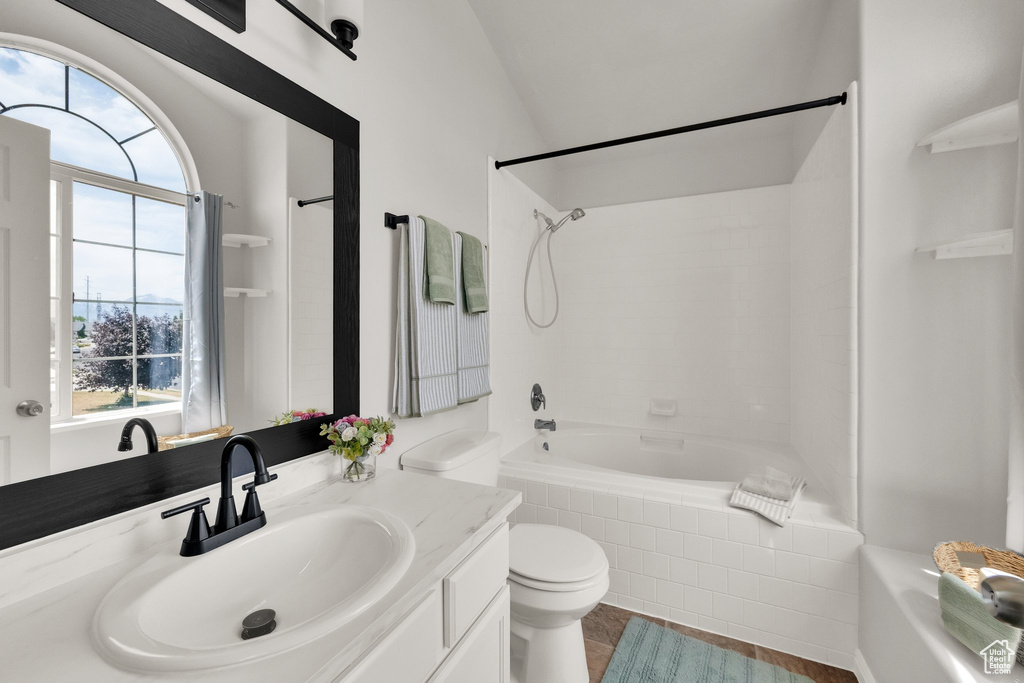 Bathroom featuring shower / tub combination, vanity, vaulted ceiling, and tile patterned floors