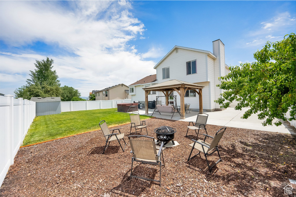 Back of property with a fire pit, a gazebo, a patio, a chimney, and a fenced backyard