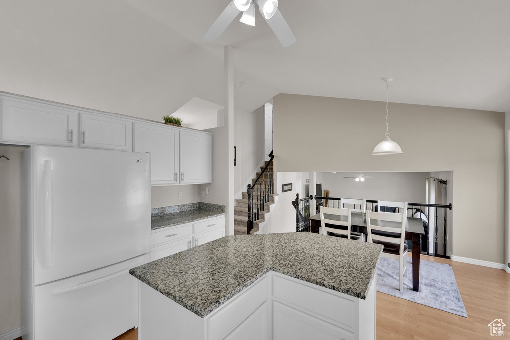 Kitchen featuring freestanding refrigerator, ceiling fan, high vaulted ceiling, white cabinetry, and light stone counters