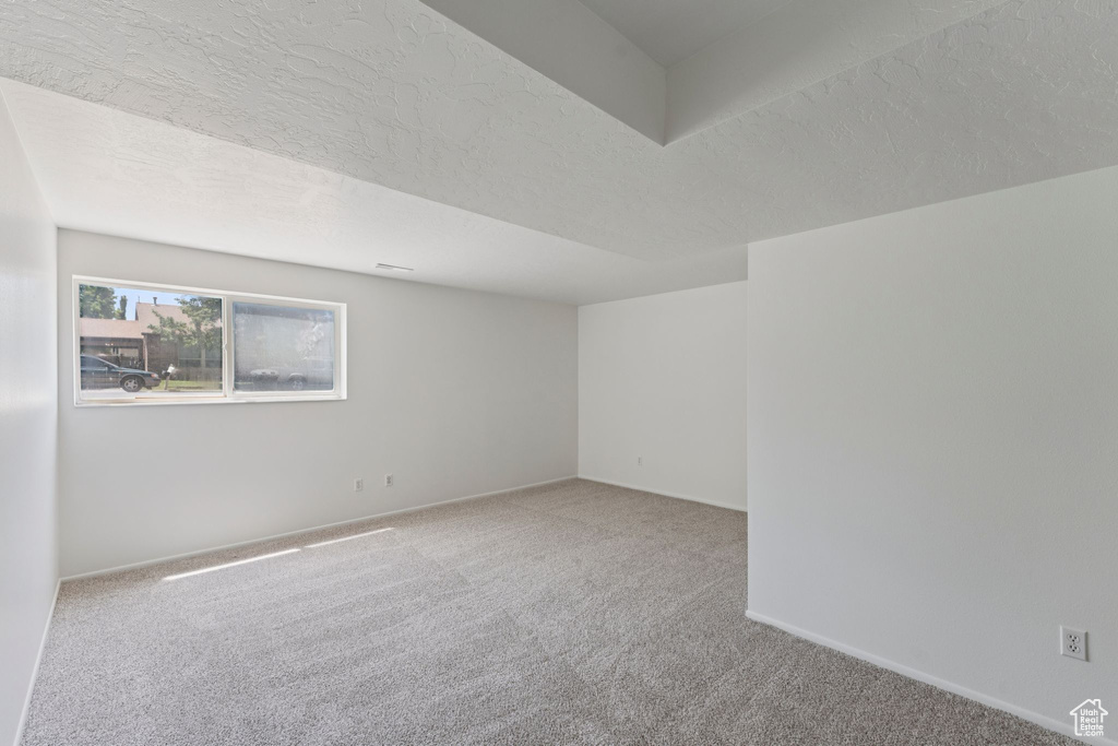 Carpeted empty room featuring baseboards and a textured ceiling