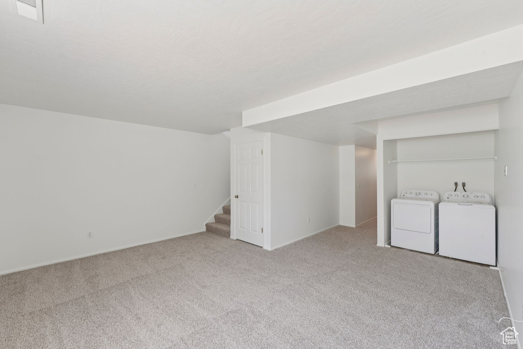 Finished below grade area featuring washer and clothes dryer, carpet, and stairway